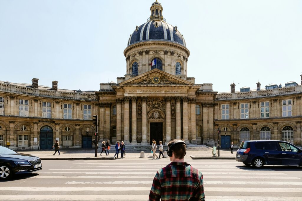 Front view of the historic Institut de France with people crossing the street in Paris.
